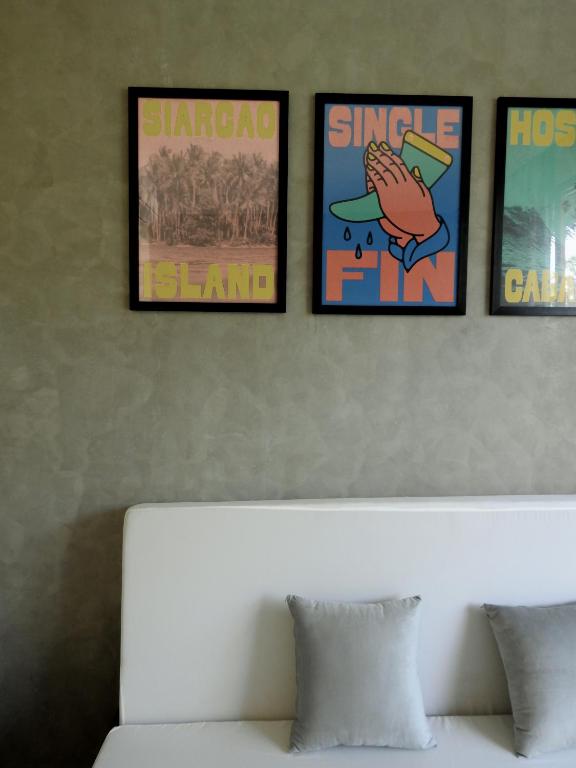 Lounge area with Siargao Island and Single Fin poster artwork on wall, white sofa with pillows