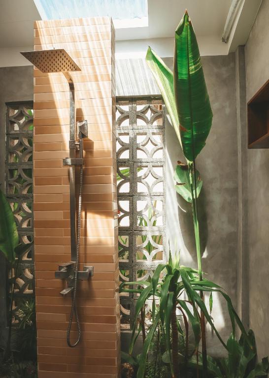 Open-air tropical shower with decorative breeze blocks and banana leaf plant