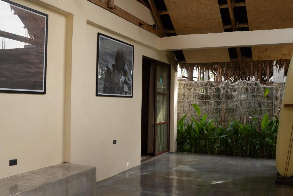Single Fin hallway with surf photography on wall, plants, and surfboard leaning against wall